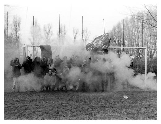 Die Nordstrandhooligans. Umgeben von einer Rauchwolke entstanden aus brennendem Salpeter, Zucker und Kaliumpermanganat. 1991.