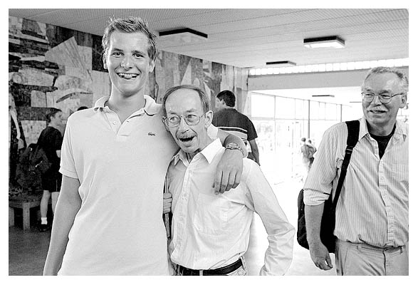 Friedrich F&uuml;lscher nimmt Herrn Martin in den Arm. Diederich am&uuml;siert sich. 2003.